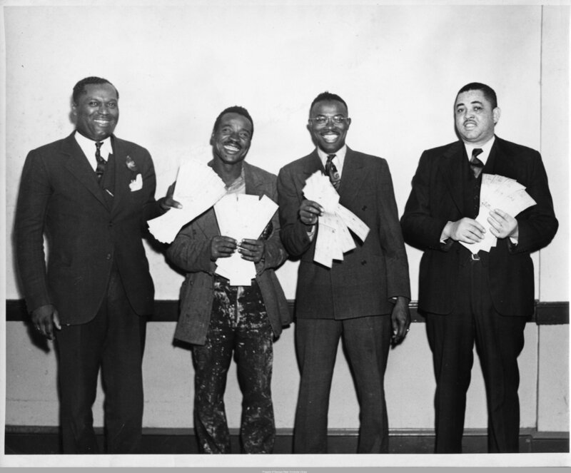 Four African-American union members pose with back pay checks